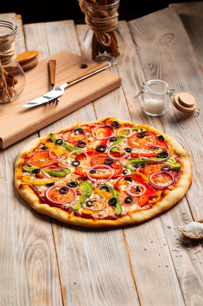 Vegetable pizza with olives and pepper on the wooden table