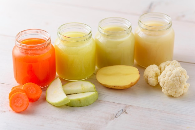 Vegetable purees in glass jars on white wooden background baby food concept