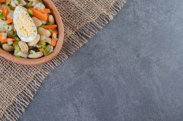 Vegetable salad in bowl on a burlap napkin on the marble surface