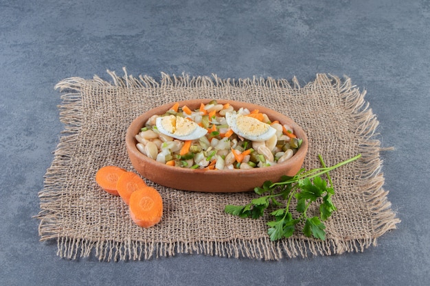 Vegetable salad in bowl on a burlap napkin on the marble surface