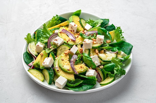 Photo vegetable salad with avocado cucumber fresh herbs and feta on a gray background side view closeup