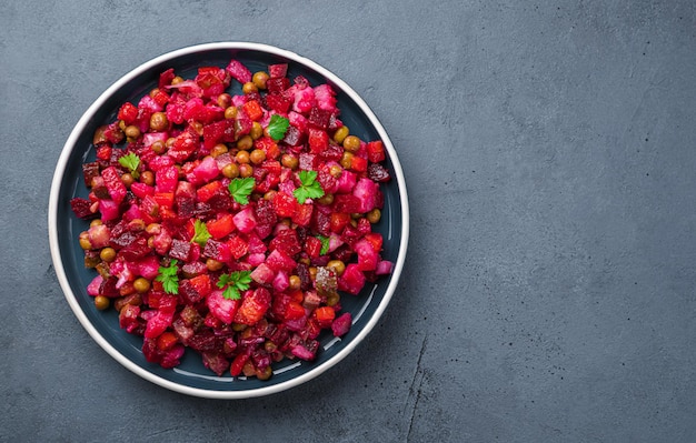 Vegetable salad with beetroot pickled cucumbers and peas on a dark background