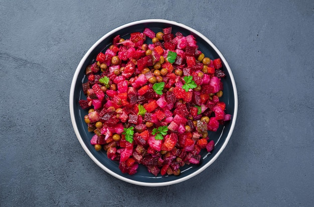 Vegetable salad with beetroot pickled cucumbers peas and fresh herbs on a dark background