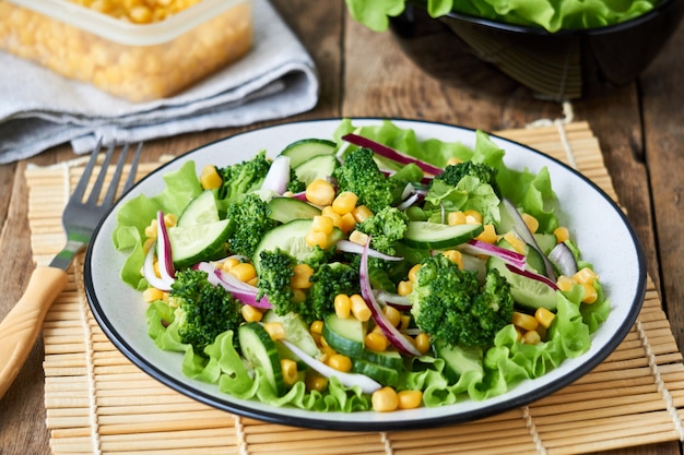 Vegetable salad with broccoli, corn and cucumbers on a plate