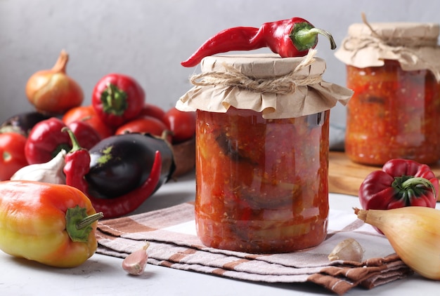 Vegetable salad with eggplant, carrot, peppers, onion and tomatoes in glass jars. Horizontal format.