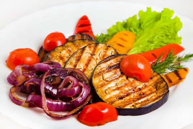 Vegetable salad with grilled eggplant, cherry tomatoes, red and yellow bell peppers, purple onions, dill, lettuce leaf