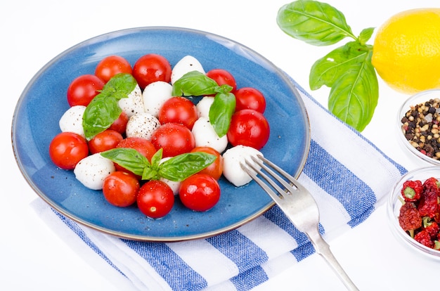 Vegetable salad with mozzarella balls on plate, white background. Studio Photo.