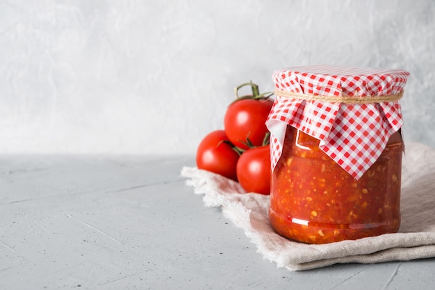 Vegetable sauce adjika with tomatoes, garlic, bell peppers in jar.