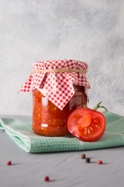 Vegetable sauce adjika with tomatoes, garlic, bell peppers in jar.