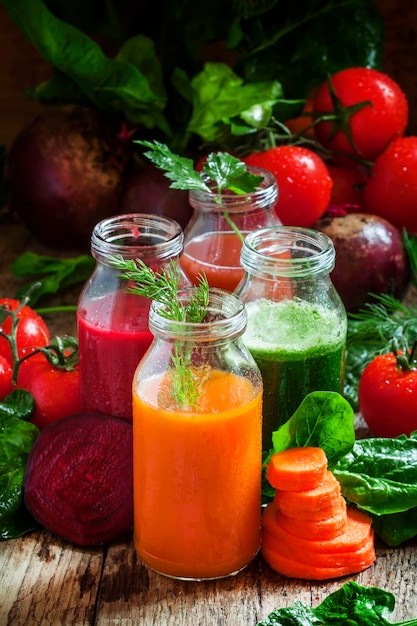 Vegetable smoothie in small bottles dark wood background selective focus.