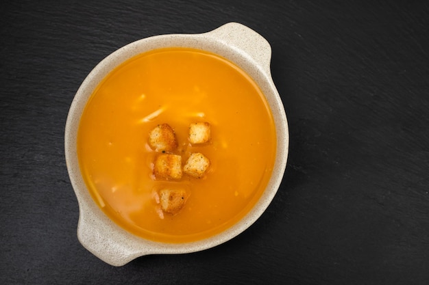 Vegetable soup with crackers in white bowl on ceramic