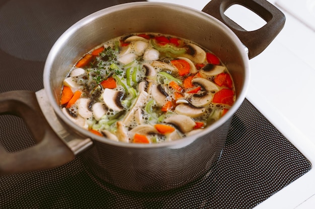 Vegetable soup with mushrooms carrots and onions in a pot