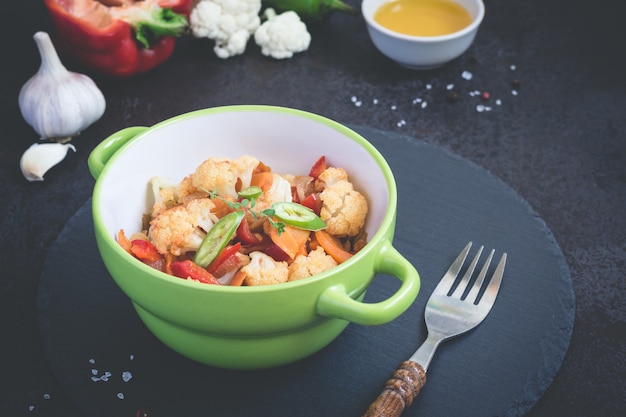 Vegetable stew and ingredients on a black background, toned