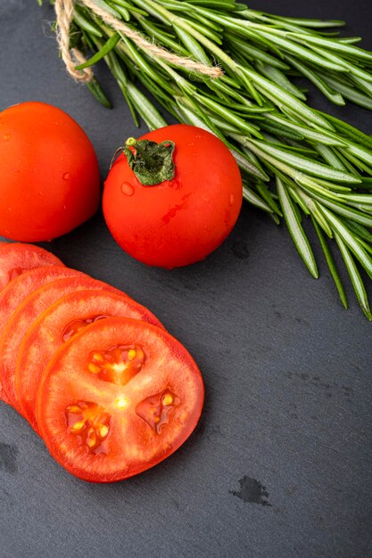 Vegetable table. Cucumbers, tomatoes and rosemary on a black table