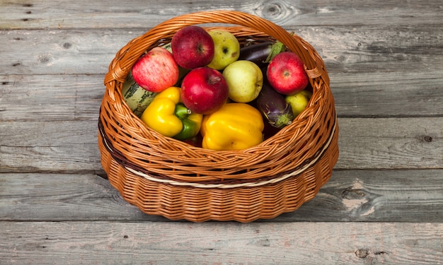 Vegetables and apples in basket on old wood table