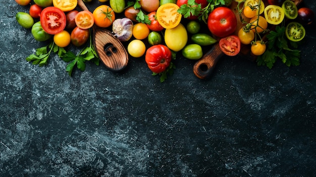 Vegetables Fresh colored tomatoes On a black stone background Top view Free space for your text