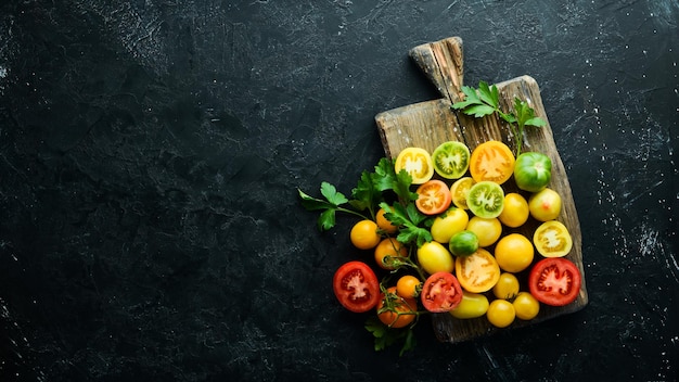 Vegetables Fresh colored tomatoes On a black stone background Top view Free space for your text