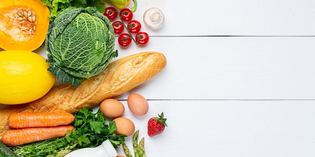 Vegetables, fruits assortment and bottle of milk on white wooden background. Vegetarian healthy food concept. Food and grocery shopping.