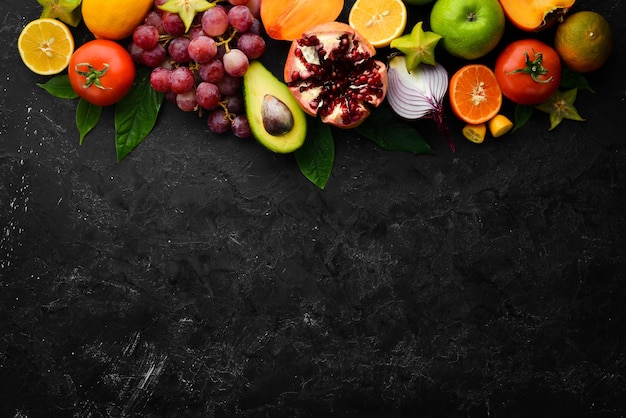 Vegetables and fruits healthy food Fruits and vegetables on black stone background Tropical fruits Top view Free space for your text