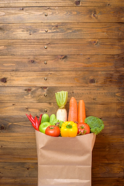 Vegetables in grocery bag on wood background