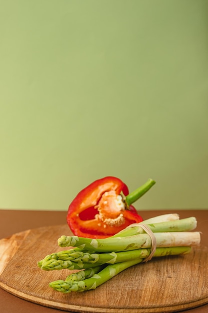 Vegetables lie on a wooden board asparagus red bell peppers brown light green background place for text