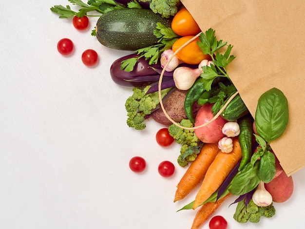 Vegetables in paper bag on white background.