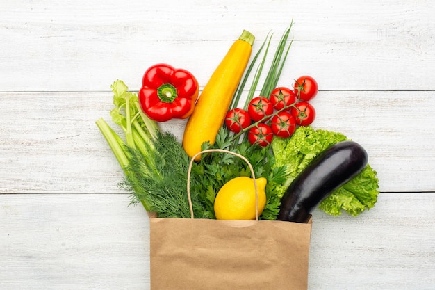 Vegetables in a paper bag on a white wooden background. Shopping in a supermarket or market.