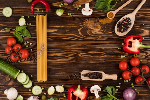 Vegetables and pasta on a wooden board. Top view.