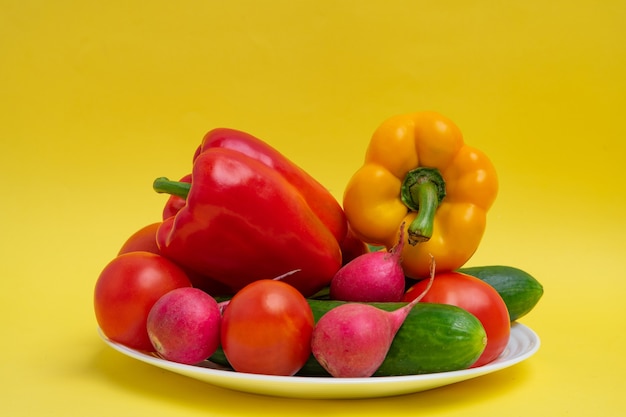 Vegetables on a plate, organic vegetables on a yellow background