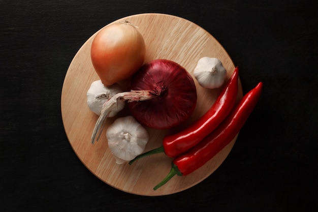 Vegetables red pepper, onions and garlic on a wooden stand.