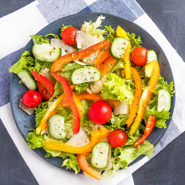 Vegetables salad with pepper tomato and cucumber on a plate Top view