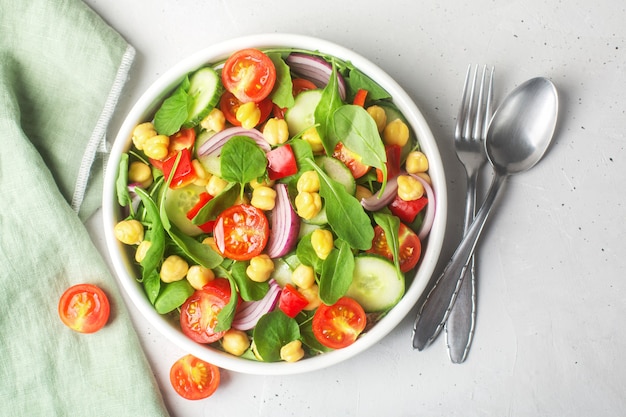 Vegetarian chickpea beans salad prepared with tomatoes, cucumber, red onion, cress salad and arugula. Chickpeas are rich in protein and fiber. Top view