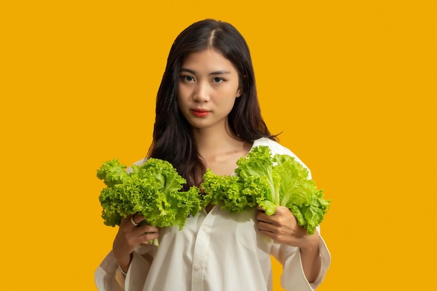 Vegetarian concept Healthy woman in white shirt hold fresh lettuce on isolated yellow background