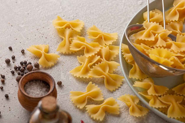 Vegetarian cooking pasta with vegetables, raw ingredients on light concrete