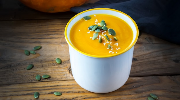 Vegetarian cream soup with pumpkin and seeds in white bowl