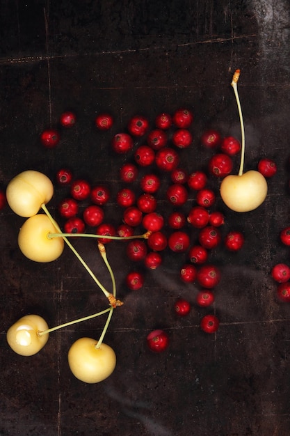 Vegetarian food concept Sweet juicy red currants and yellow cherries on a dark background View from above