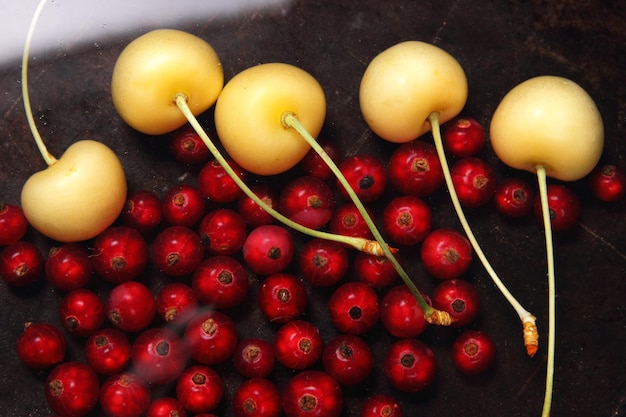 Vegetarian food concept Sweet juicy red currants and yellow cherries on a dark background View from above