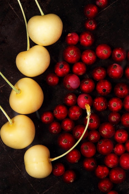 Vegetarian food concept Sweet juicy red currants and yellow cherries on a dark background View from above