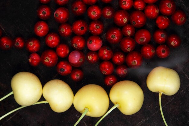 Vegetarian food concept Sweet juicy red currants and yellow cherries on a dark background View from above