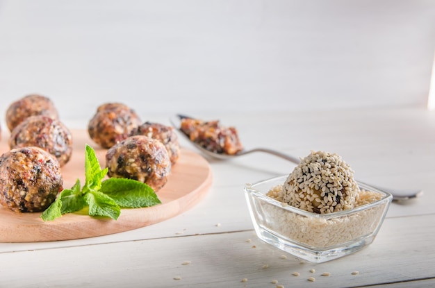 Vegetarian food, homemade energy balls of walnuts, dates, prunes, cranberries and honey with sesame on white background