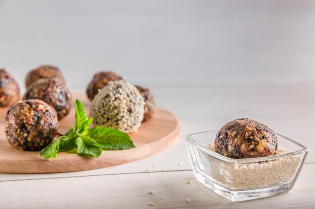 Vegetarian food, homemade energy balls of walnuts, dates, prunes, cranberries and honey with sesame on white background