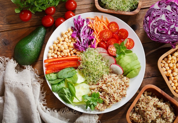 Vegetarian food. Plate of healthy salad with  avocado, quinoa, tomato, pepper, spinach, cabbage, sprouts and chickpeas, top view