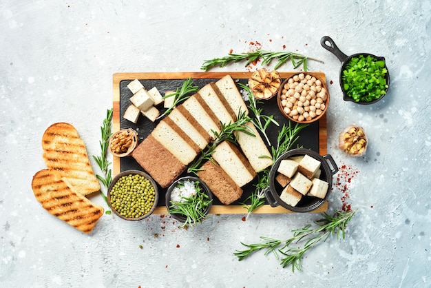 Vegetarian food Tofu cheese with rosemary cut into pieces on a board On a stone background