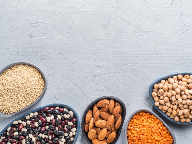 Vegetarian healthy protein sources on gray concrete background quinoa chickpea almond red lentils mixed bean as vegan sources of protein concept close up top view or flat lay copy space