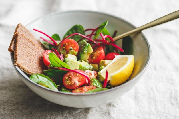 Vegetarian healthy salad is made from swiss chard leaves cherry tomatoes avocado lemon juice and olive oil into a ceramic portion bowl