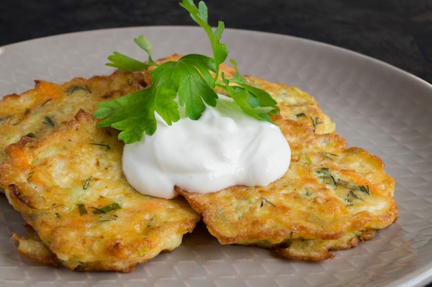 Vegetarian healthy zucchini pancakes with herbs and sour cream