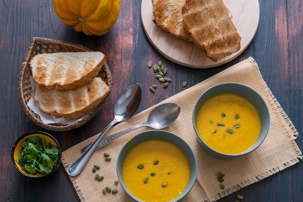 Vegetarian homemade pumpkin cream soup with seeds and bread.