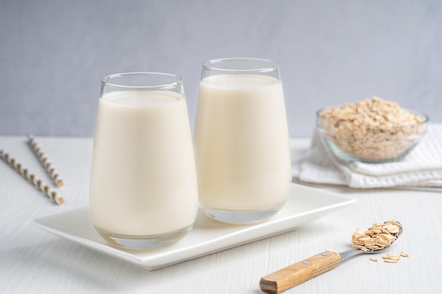 Vegetarian lactose free oat milk made from whole grains with creamy texture in drinking glass