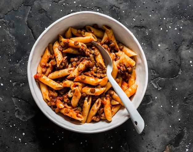 Vegetarian lentil Bolognese sauce penne pasta on a dark background top view