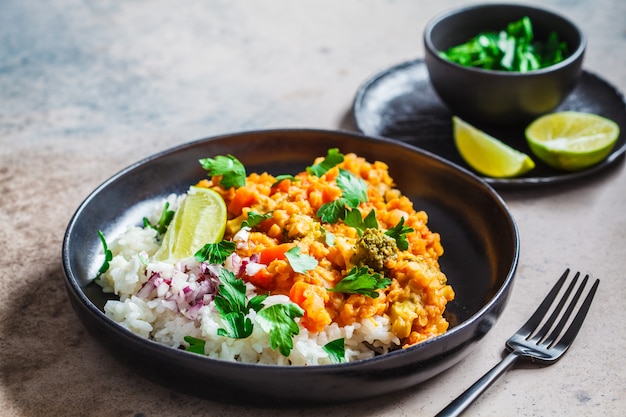 Vegetarian lentil curry with rice in black plate. Healthy vegan food concept.